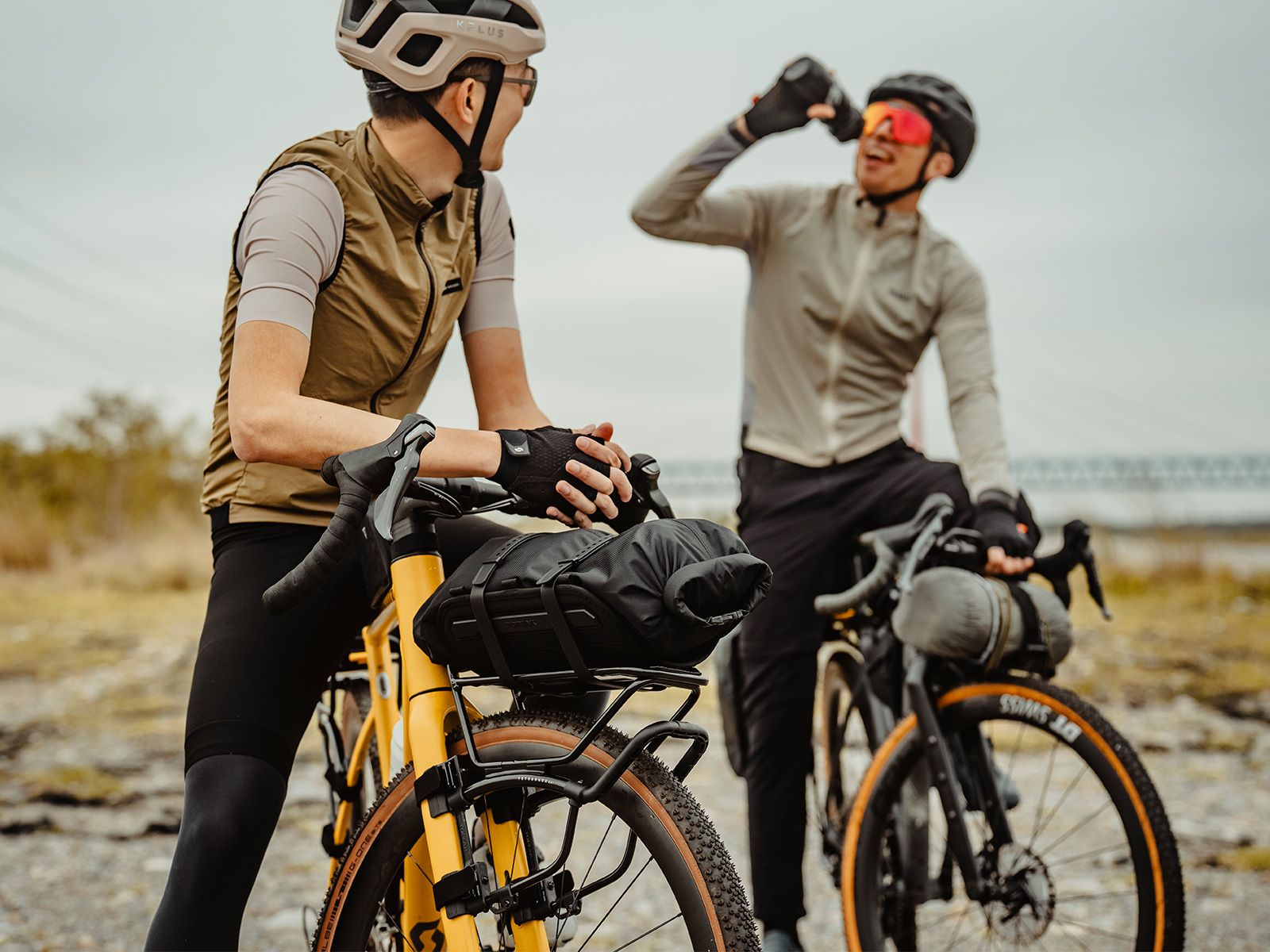 Zwei Männer stehen mit ihren Gravelbikes nebeneinander. Das Linke Bike hat den Topeak TetraRack GR1 montiert und ein Packsack ist auf dem Gepäckträger befestigt.