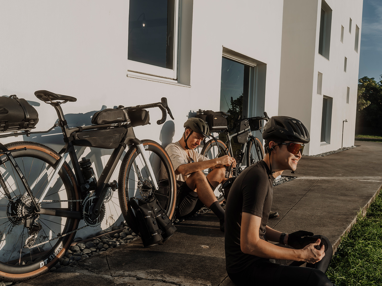  Zwei Männer sitzen vor ihren Bikes, eines der Velos ist mit der Topaek MidLoader Drybag Rahmentasche in Gr L in schwarz ausgestatttet