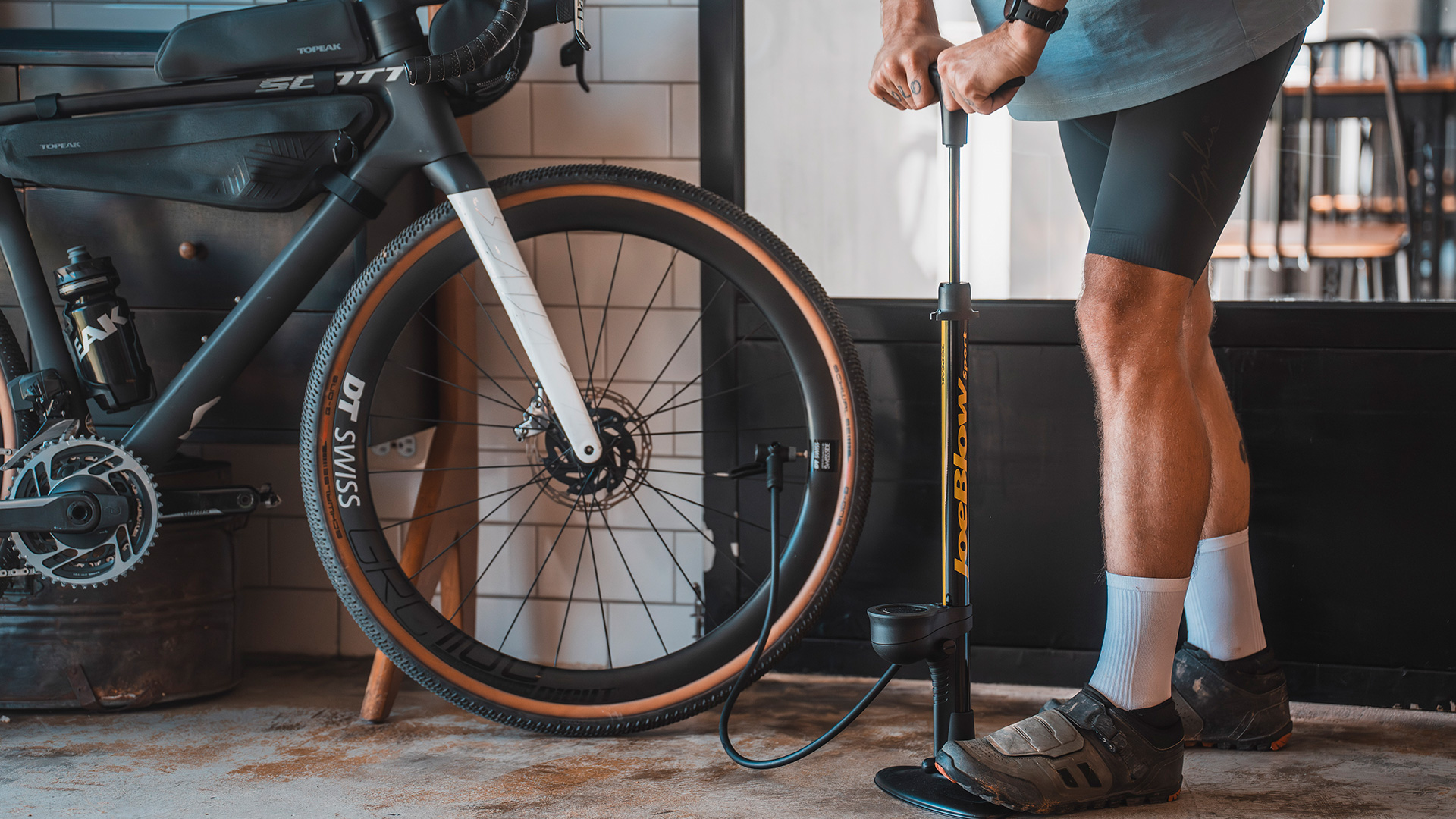 Person pumpt ein Gravelbike-Reifen mit der Topeak Joeblow Sport Digital 2.0 Standpumpe – schwarze Pumpe mit gelbem Logo und digitalem Display, angeschlossen am Velo.