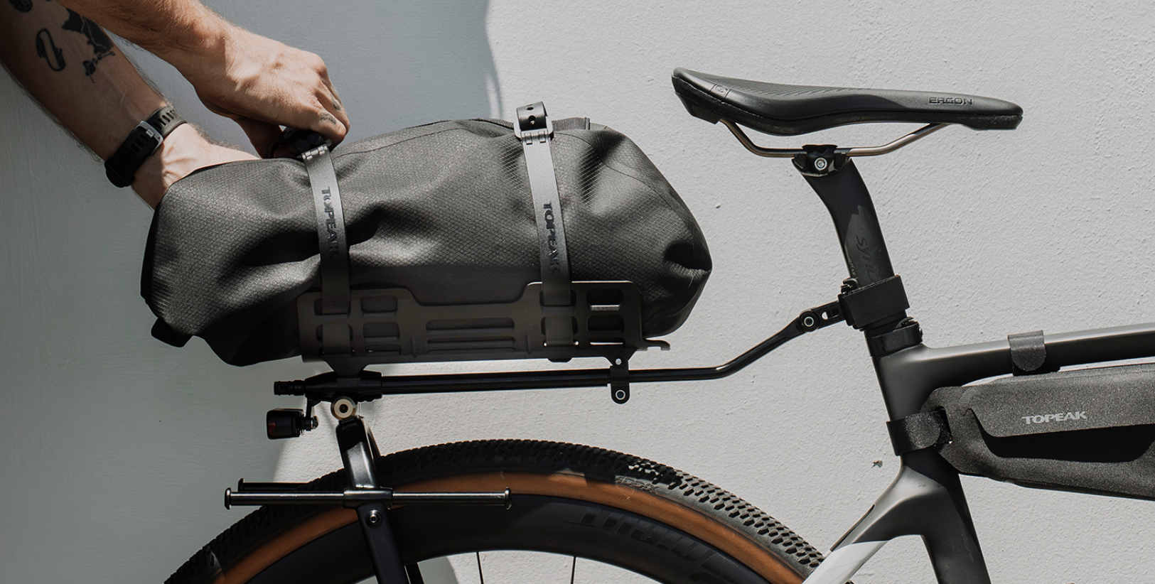 Topeak U-Shell Drybag mit 10 Liter in schwarz Gepäckträgertasche, zeigt wie ein Mann die Tasche auf dem Zi:Rak System mit den Gurent fixiert