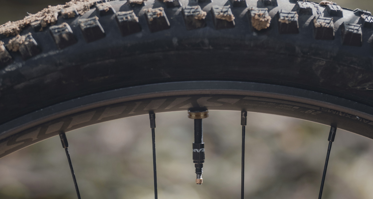 Nahaufnahme eines RapidHead-Pumpenkopfes, der an ein Tubeless-Ventil eines Mountainbike-Reifens angeschlossen ist, im Outdoor-Einsatz.