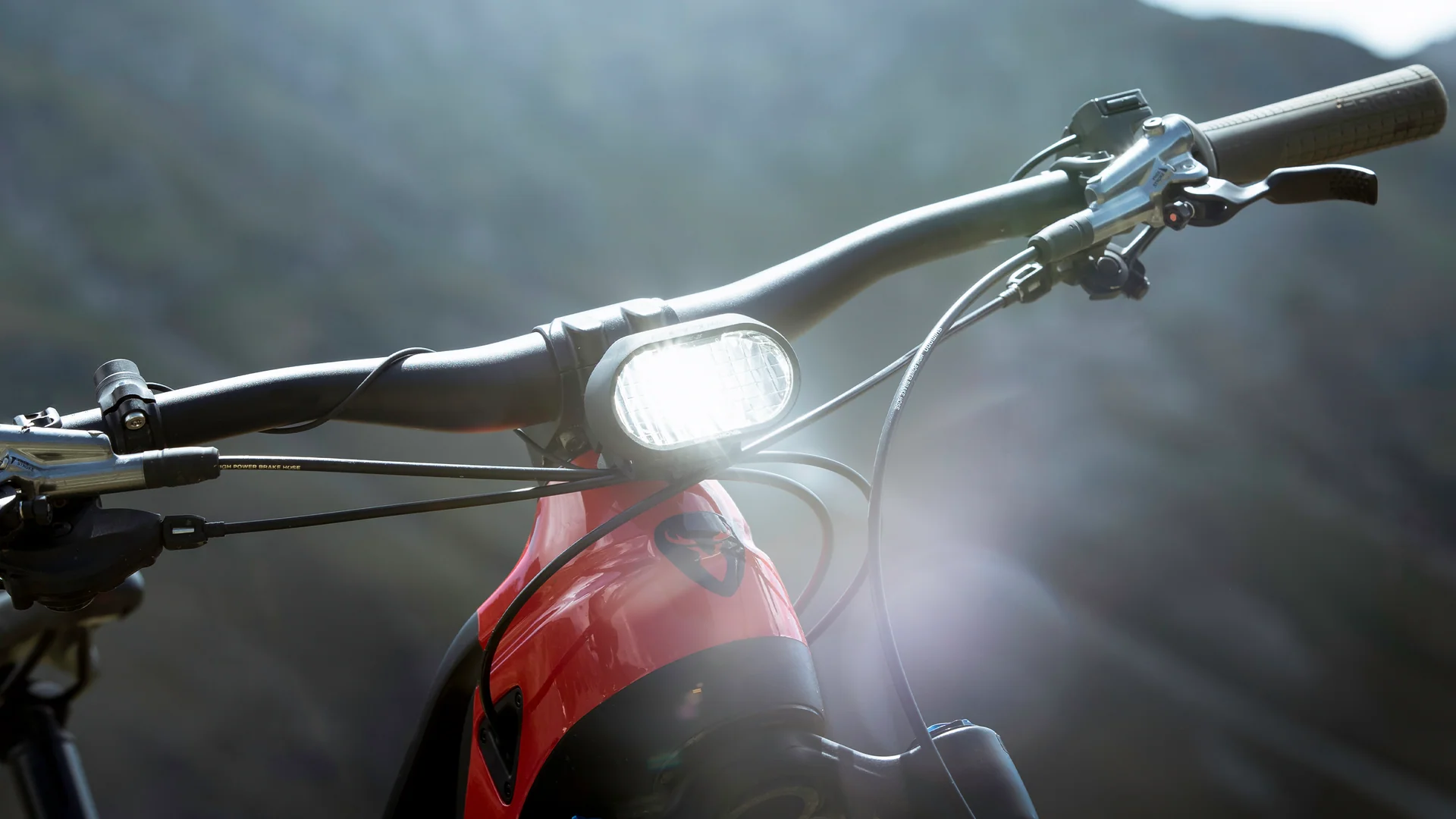 eingeschalteter Supernova M99 Mini Pro Scheinwerfer am Lenker eines roten E-Bikes