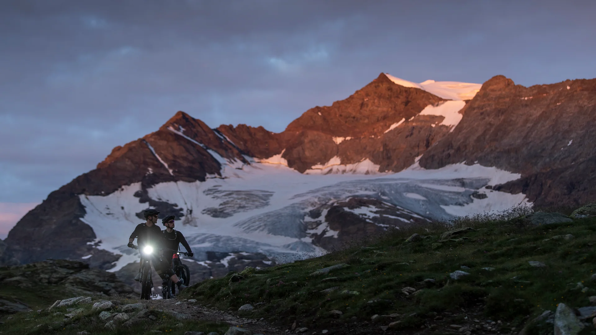 E-MTB mit hellem Scheinwerfer vor Gletscher im Hochgebirge