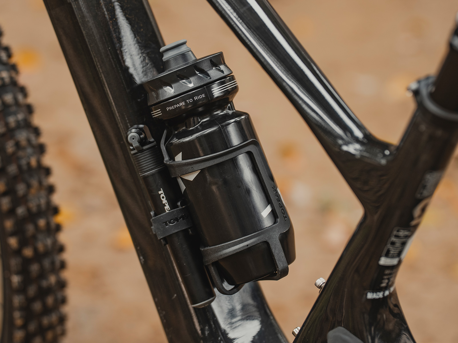 Topeak Flaschenhalter montiert an einem schwarzen Fahrrad mit Flasche und Pumpe an der Seite