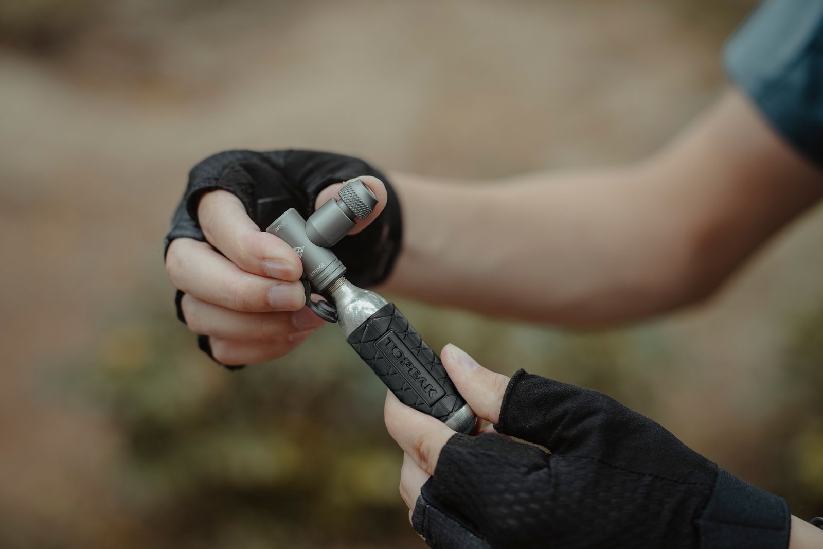 Hände halten den Topeak Airbooster II CO2 Pumpenkopf 