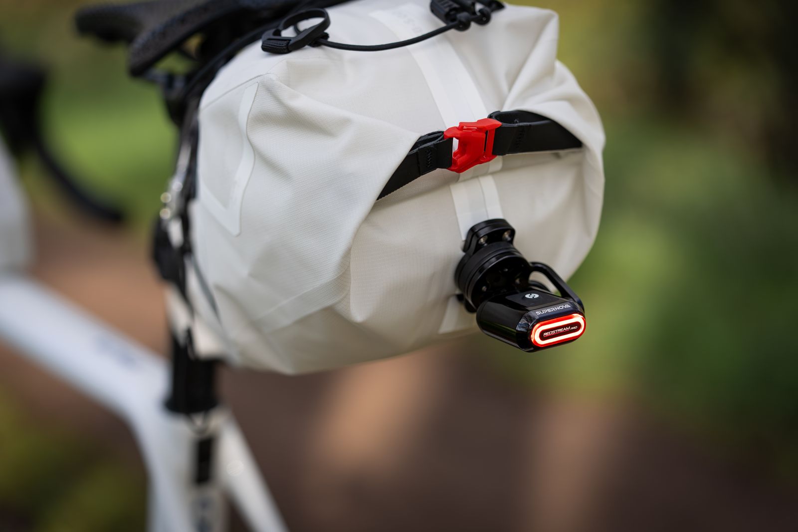 Supernova Redstream Pro Ruecklicht in Schwarz unter dem Velosattel mit rotem Lichtstrahl nach hinten.