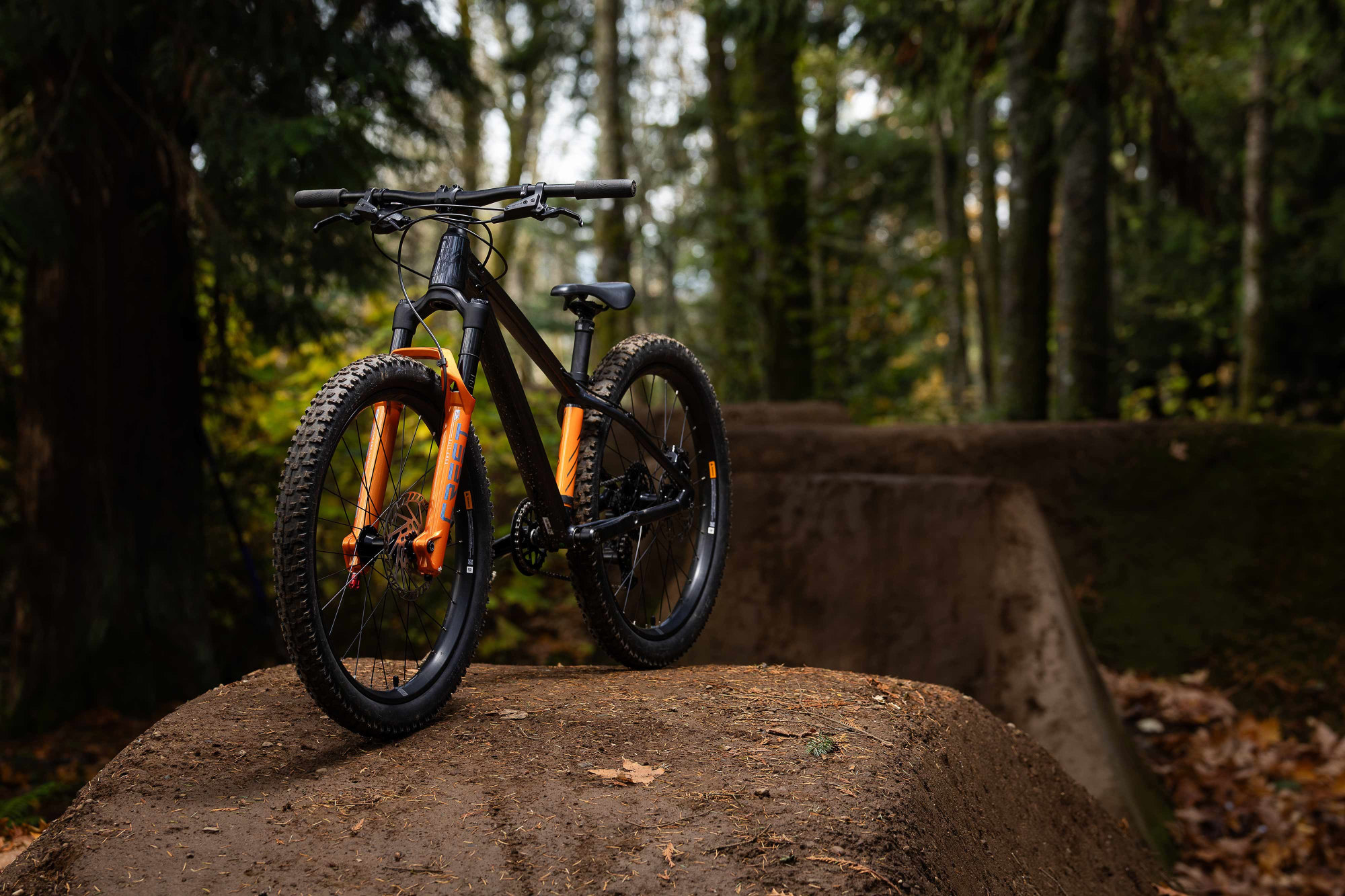 VTT semi-rigide dirt 24 pouces Giant STP 24, vue en forêt trois-quarts avant gauche