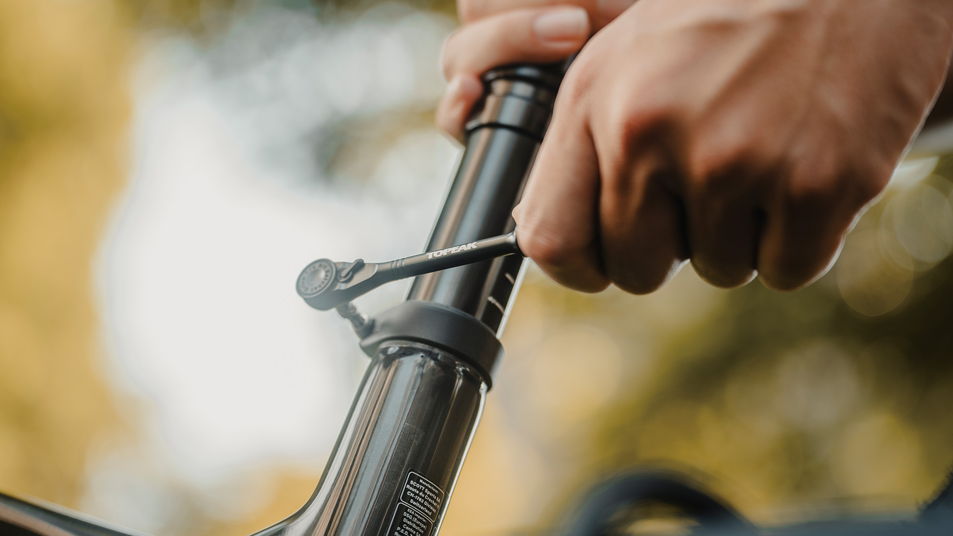 Eine Person zieht mit der Topeak Ratchet Toolbar Aluminium eine Schraube am Fahrradrahmen fest – kompaktes, präzises Werkzeug für unterwegs.